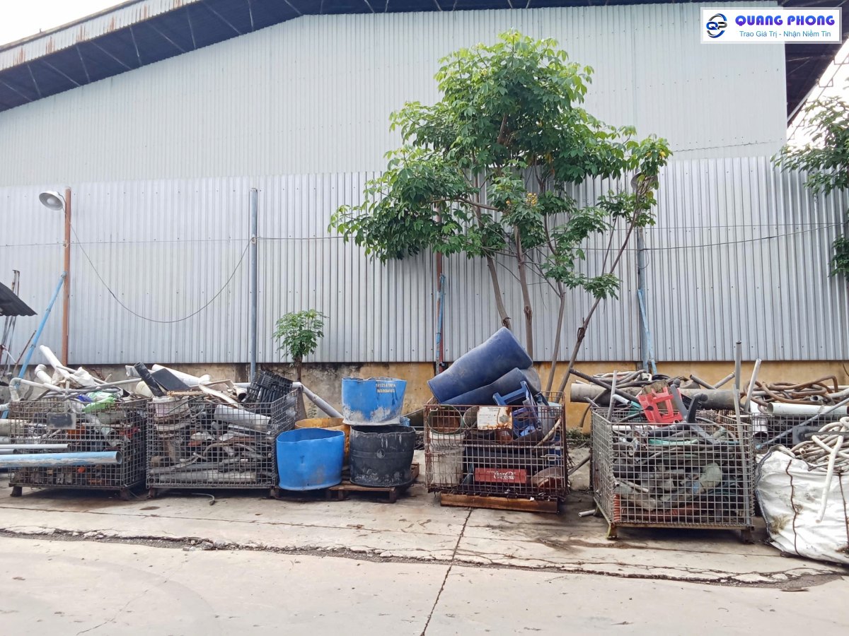 Khu tập kết phế liệu với lồng thép lưới và thùng chứa phân loại cạnh nhà xưởng